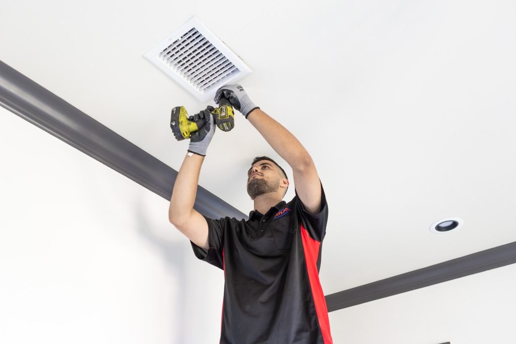Technician drilling to install a new vent for air duct system.