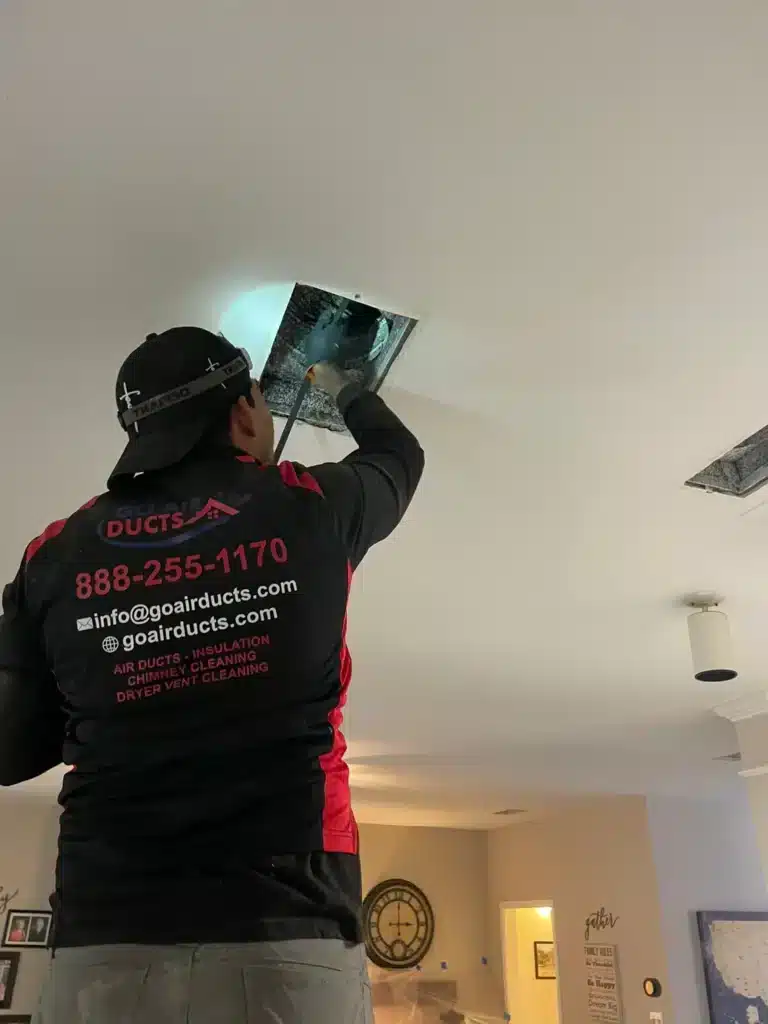 Technician cleaning ceiling air duct vent