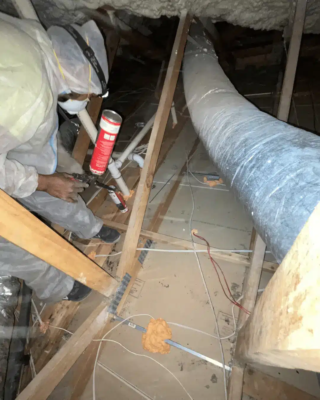 Technician applying sealant to attic ductwork