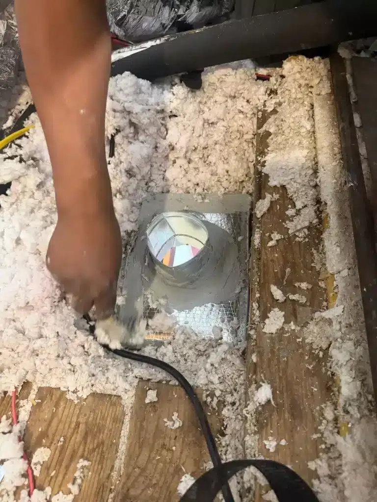 Technician sealing ductwork in attic