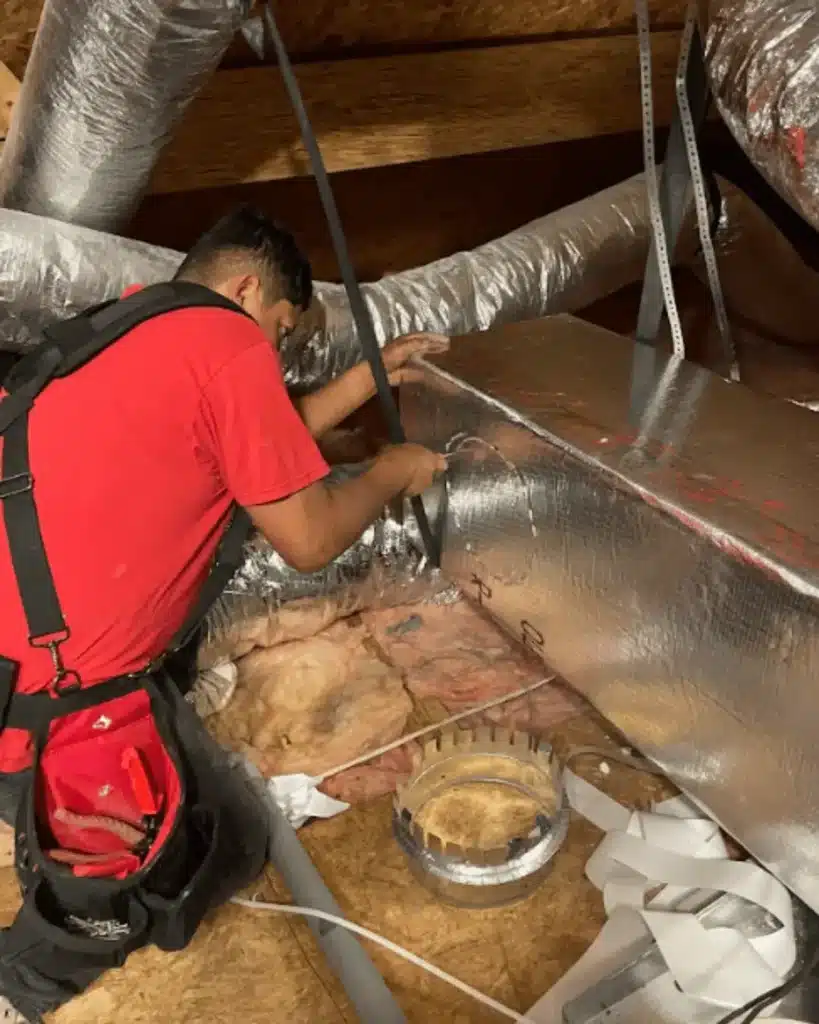 Technician working on ductwork in attic