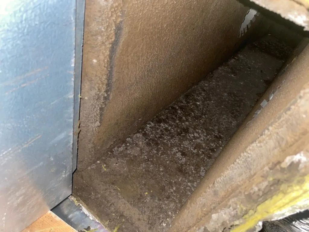 Dust and debris buildup inside a dirty HVAC duct before professional cleaning.